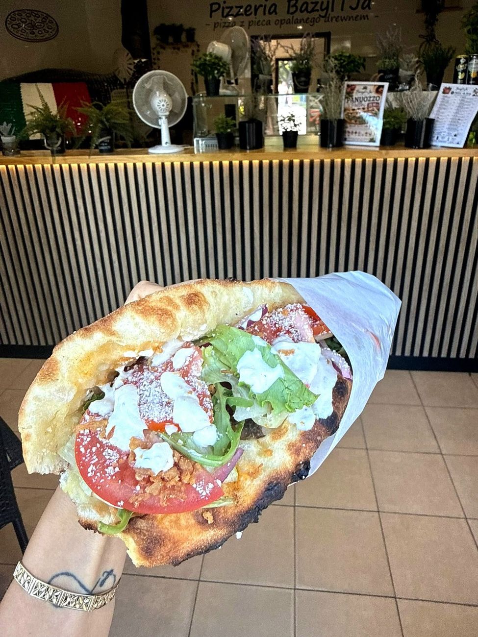 Panuozzo w papierze na tle lady pizzerii